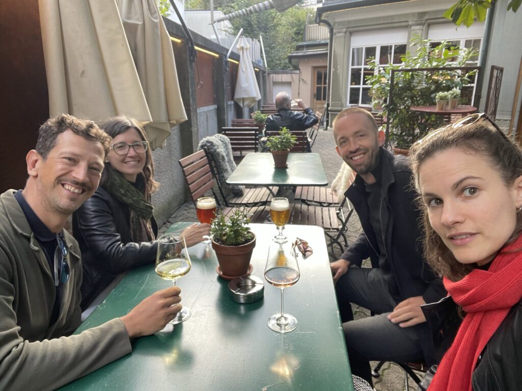 Investigate Europe and Reflekt posing for a photo, having an informal drink at an outside table during their study visit.